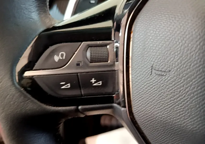 Gros plan sur les commandes vocales et volume au volant cuir noir du Peugeot 2008 gris clair, version 2021.