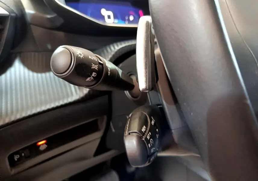 Gros plan sur les commandes au volant du Peugeot 2008 2021, montrant les leviers de clignotants et régulateur, intérieur noir.