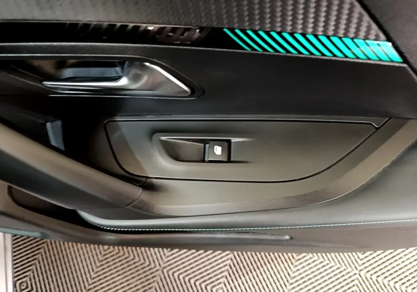 Gros plan sur la porte intérieure côté gauche du Peugeot 2008 gris clair, avec poignée argentée et commande de vitre.