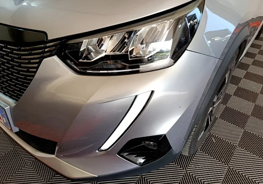 Gros plan sur l'avant droit gris clair du Peugeot 2008 2021 avec phares LED et feux diurnes en forme de griffes.