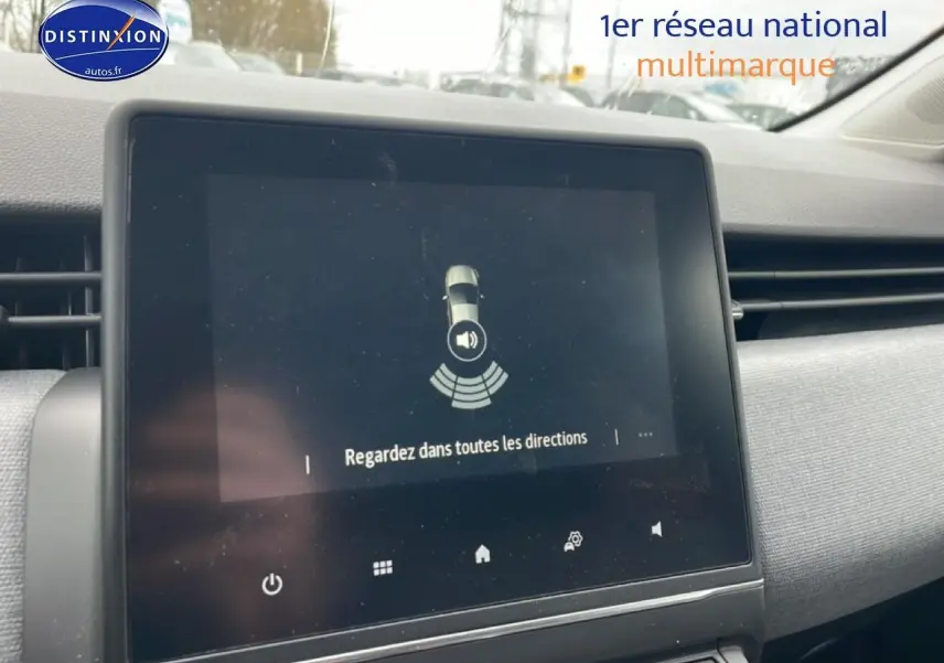 Écran tactile central de la Renault Clio V blanche, vue intérieure sur le tableau de bord avec système d’aide au stationnement.