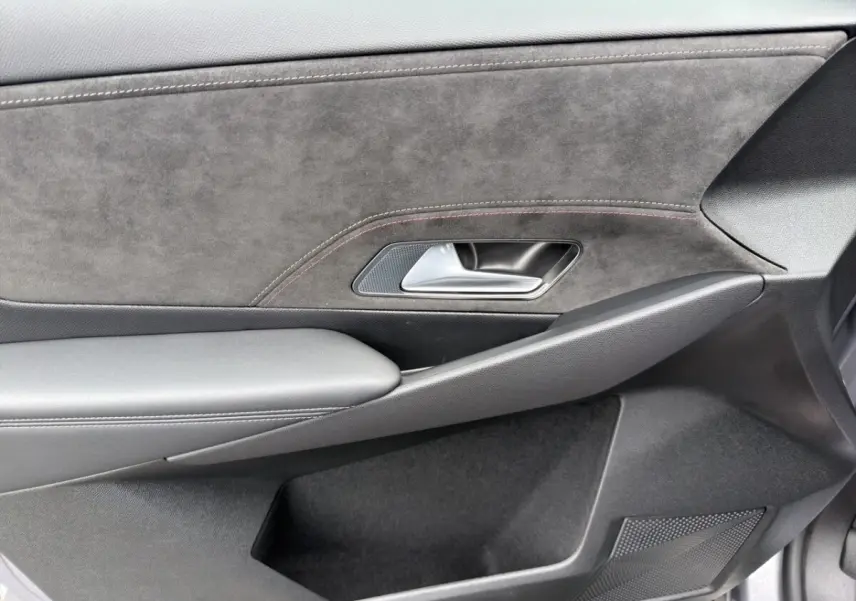 Gros plan sur la porte intérieure côté droit du DS7 Crossback gris clair, avec garniture en alcantara et poignée métal.