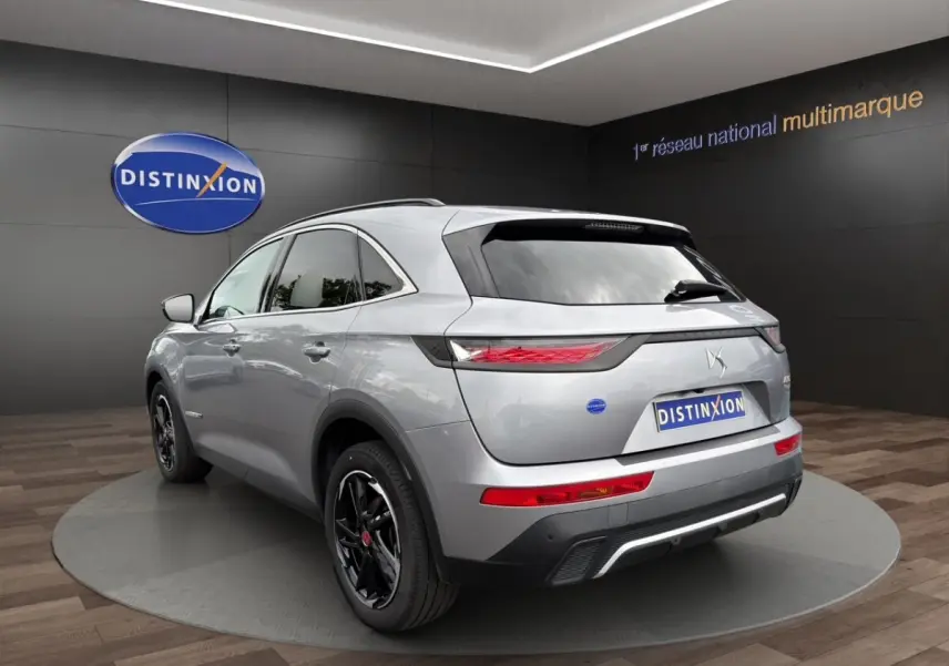 DS7 Crossback gris clair vu en 3/4 arrière droit, avec jantes noires et feux arrière LED distinctifs.