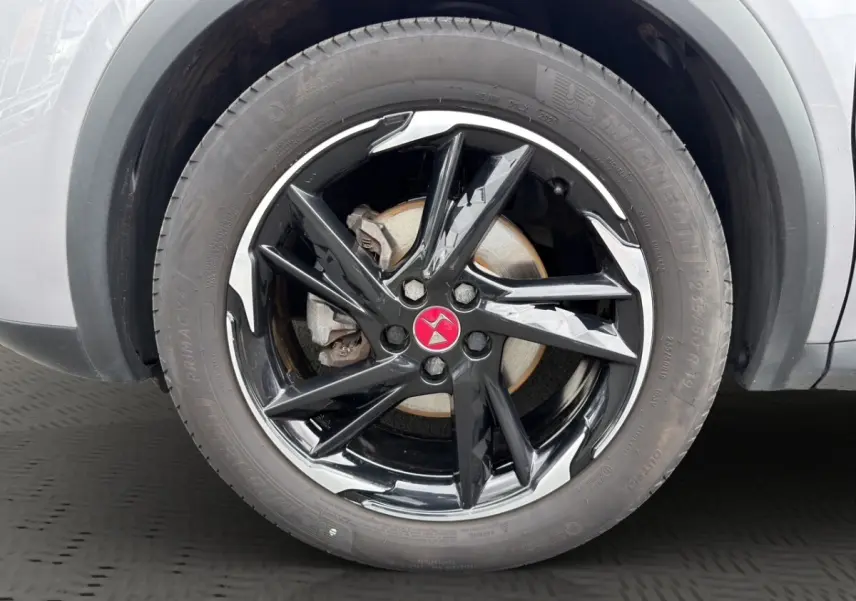 Gros plan sur la roue avant droite du DS7 Crossback gris clair, jante noire brillante avec logo rouge au centre.