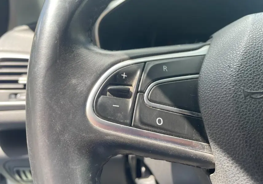 Gros plan sur les commandes de régulateur de vitesse au volant noir de la Renault Mégane IV Berline 2016.