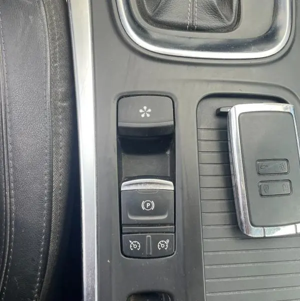 Gros plan sur la console centrale noire de la Renault Mégane IV blanche, montrant les commandes électroniques et la clé.