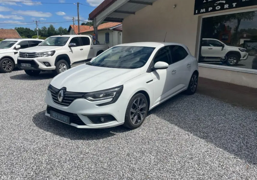 Renault Mégane IV blanche vue en 3/4 avant droit, avec jantes alliage et calandre noire distinctive.