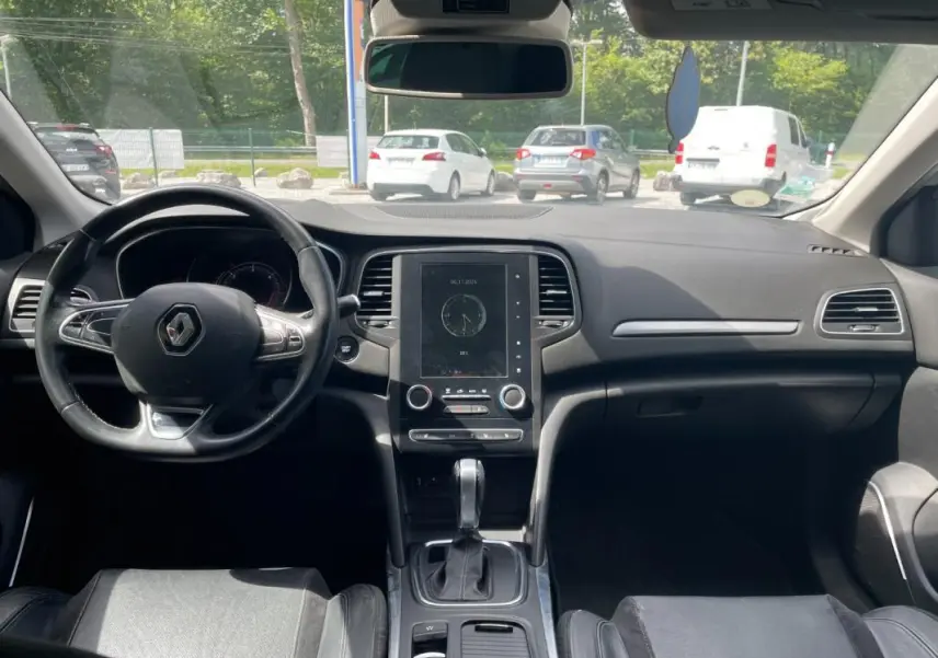 Vue intérieure frontale du tableau de bord et volant noir de la Renault Mégane IV Berline 2016, avec écran tactile central.