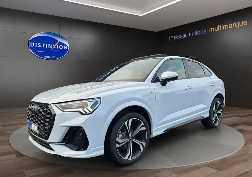 Audi Q3 Sportback blanc glacier en 3/4 avant droit, avec jantes sport noires et toit panoramique visible.