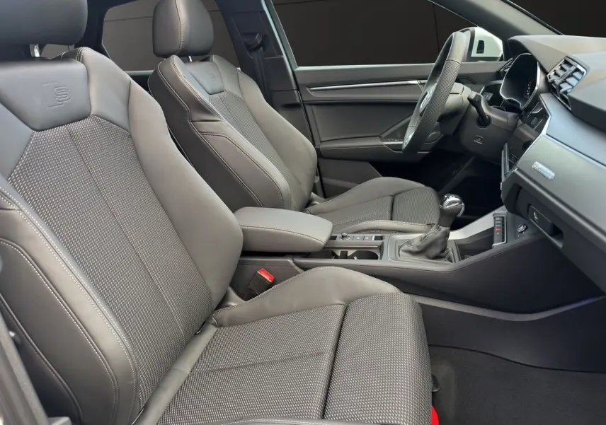 Intérieur avant de l'Audi Q3 Sportback S Line 2024 avec sièges sport noirs et console centrale moderne.