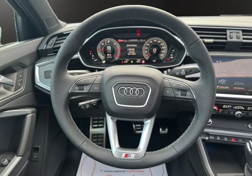 Volant sport S line en cuir perforé avec tableau de bord numérique et console centrale d'Audi Q3 Sportback 2024.