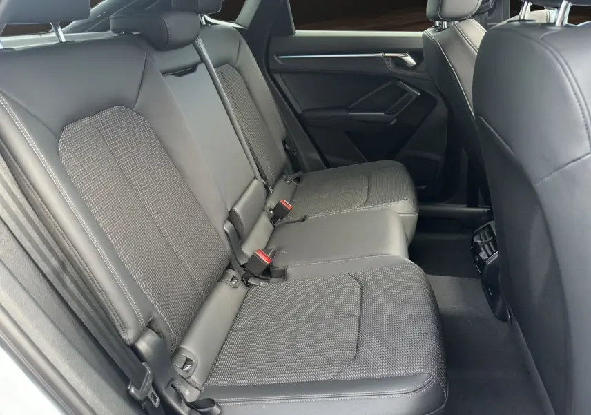 Vue côté droit de la banquette arrière en tissu noir de l'Audi Q3 Sportback S Line 2024 avec ceintures rouges visibles.