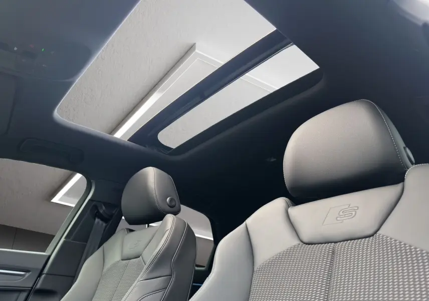 Intérieur noir de l'Audi Q3 Sportback S line 2024, sièges sport avec logo S et toit panoramique ouvert.