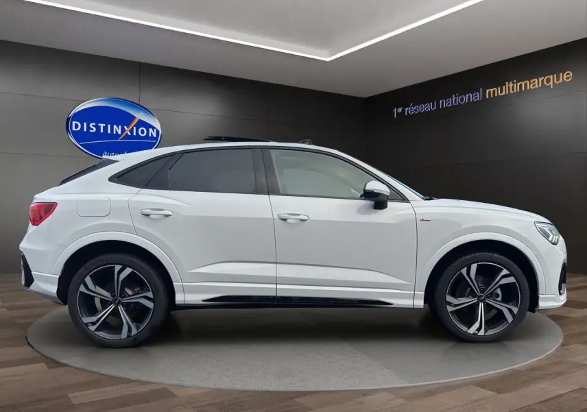 Audi Q3 Sportback blanc vue profil côté gauche avec jantes noires sport à 5 branches doubles en showroom