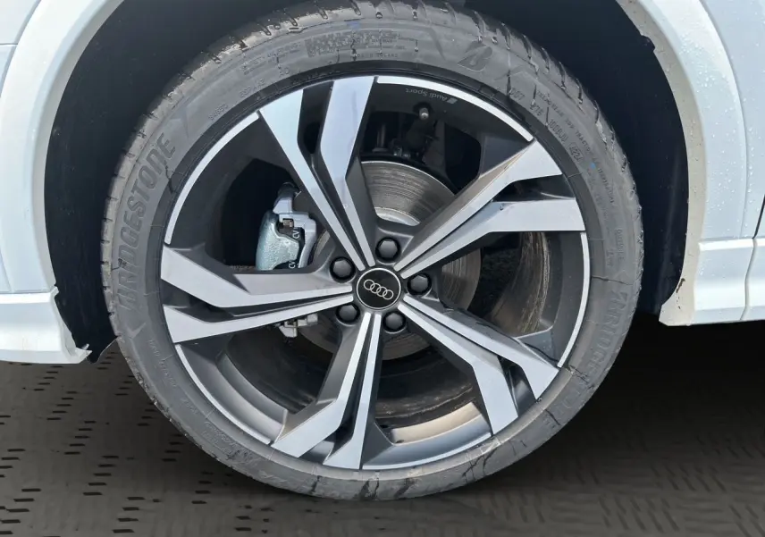 Gros plan sur la jante noire et argent à 5 branches doubles de l'Audi Q3 Sportback blanc glacier.