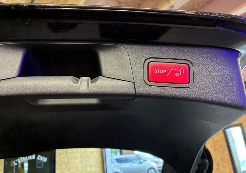 Bouton rouge stop pour hayon électrique visible sur l'intérieur du coffre d'un Mercedes Classe C Break noir métal.