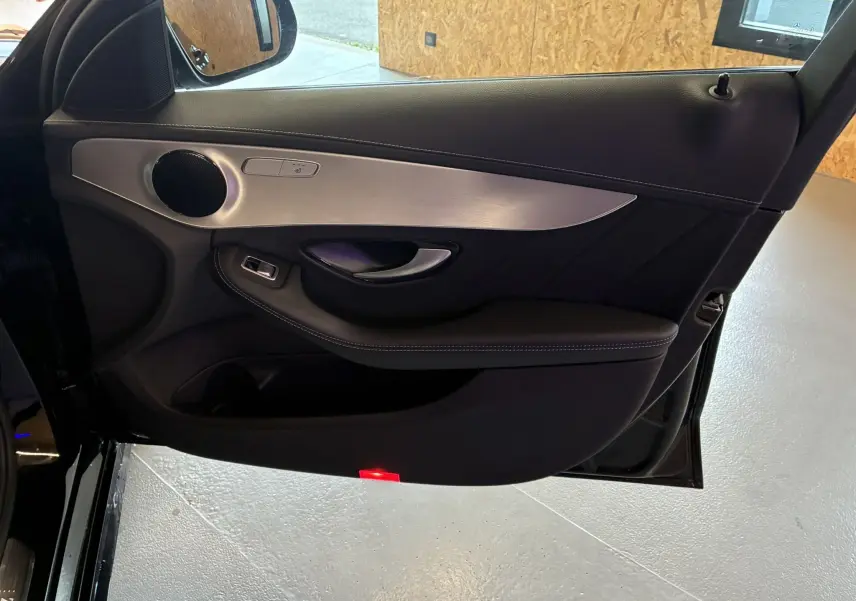 Gros plan sur la porte avant gauche noire du Mercedes Classe C Break 220D AMG Line avec insert aluminium et haut-parleur rond.
