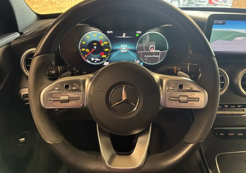 Vue rapprochée du volant cuir multifonction et du tableau de bord digital du Mercedes Classe C Break noir métal 220D AMG Line.