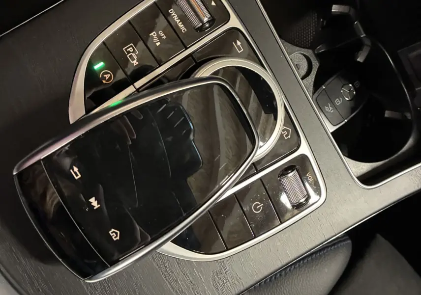 Gros plan sur la console centrale noire mate de la Mercedes Classe C Break 220D AMG Line avec pavé tactile et commandes multimédia.