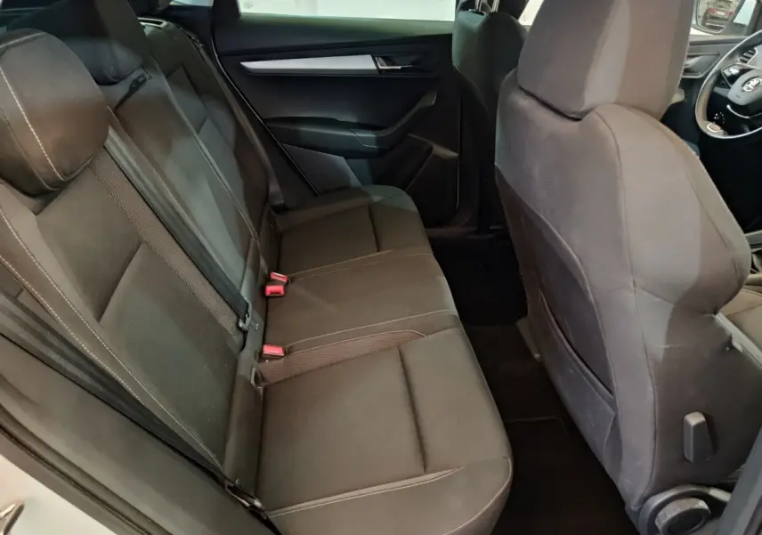 Vue intérieure côté droit montrant la banquette arrière noire du Skoda Karoq 2024 avec sièges tissu et ceintures de sécurité.