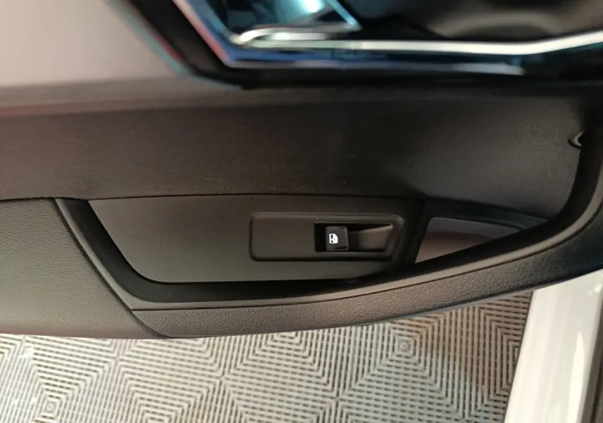 Gros plan sur le bouton de verrouillage de porte noir dans l'habitacle côté conducteur d'un Skoda Karoq blanc 2024.
