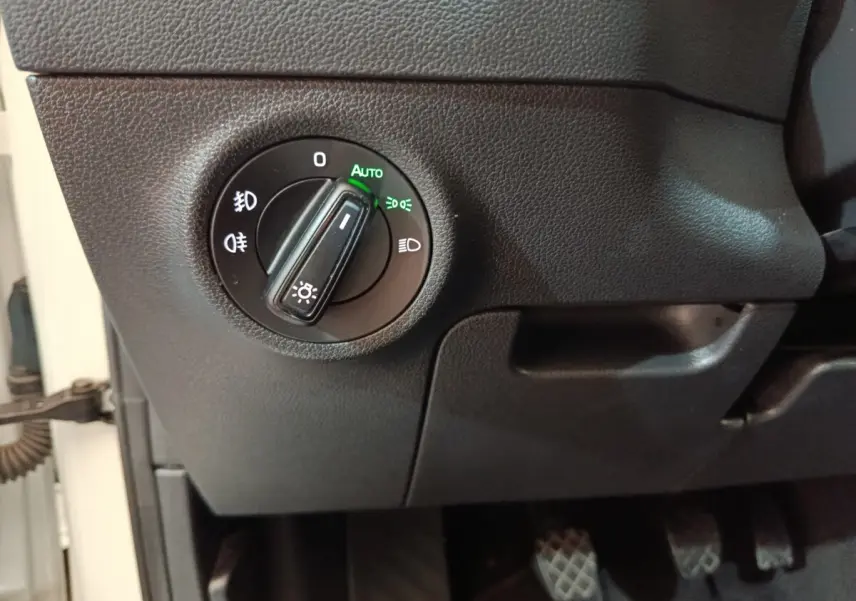 Gros plan sur le bouton de commande des phares en mode automatique dans l'habitacle d'une Skoda Karoq blanche 2024.