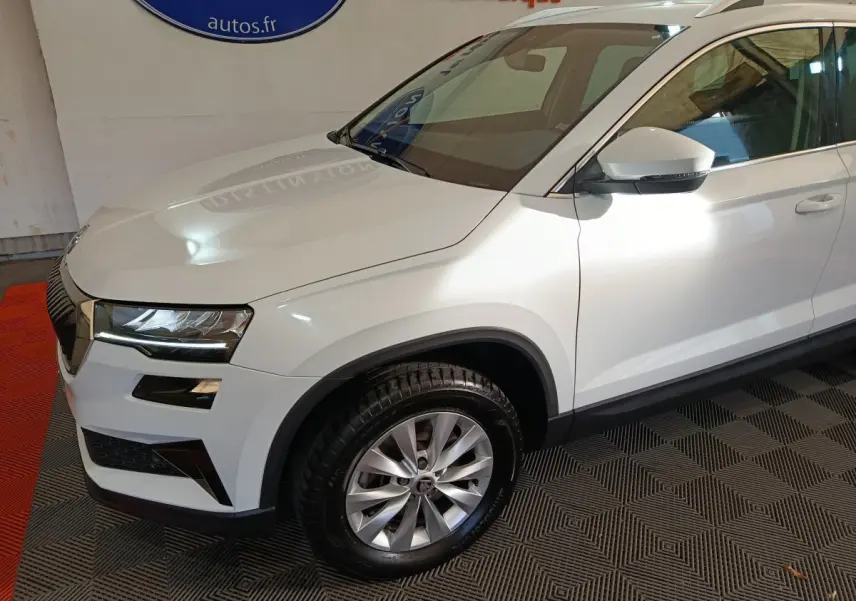 Vue 3/4 avant droit du SUV blanc Skoda Karoq 2024 avec jantes alliage et phares LED ellipsoïdaux.