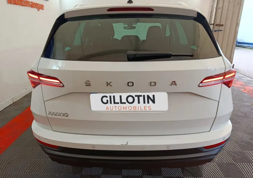 Vue arrière d'un Skoda Karoq blanc avec feux LED allumés et logo ŠKODA bien visible.