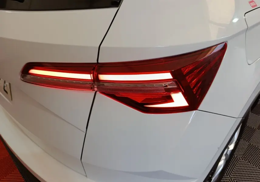 Gros plan sur le feu arrière droit allumé d’un Skoda Karoq blanc, mettant en valeur ses lignes LED modernes.
