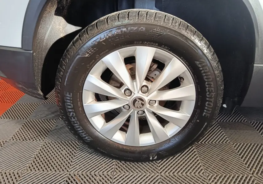 Gros plan sur la roue avant droite d’un Skoda Karoq blanc avec jante argentée et pneu Bridgestone.