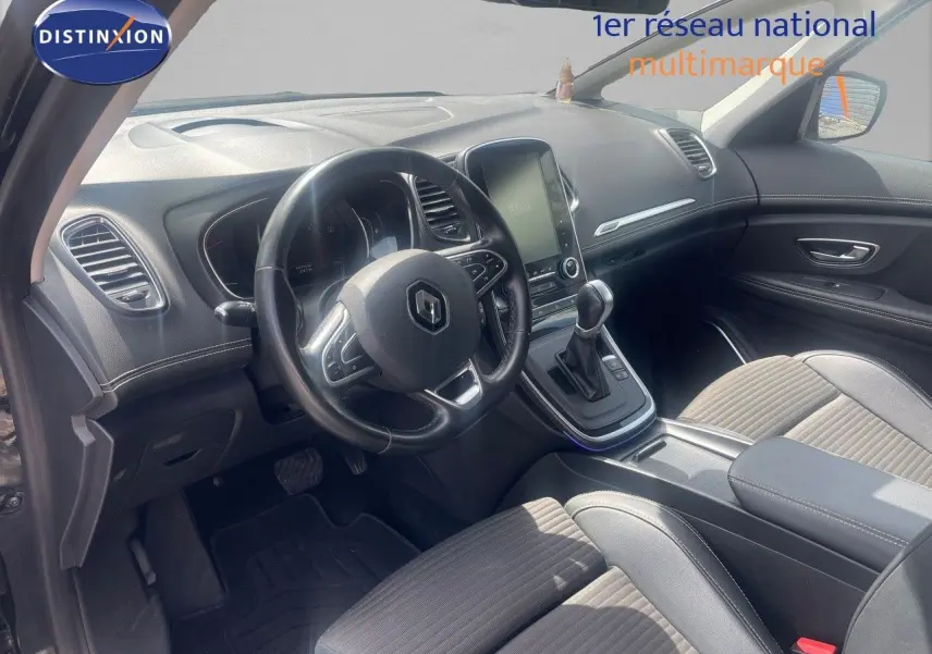 Vue intérieure côté conducteur du Renault Scénic IV noir, mettant en valeur le tableau de bord et la console centrale avec écran tactile.