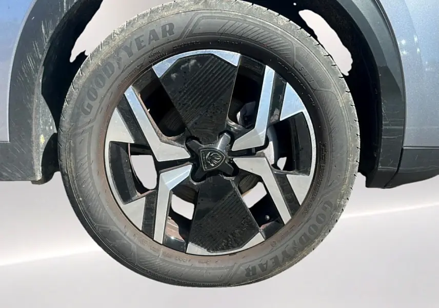 Gros plan sur la roue avant gauche du Peugeot 2008 gris Artense avec jante alu noire et grise au design géométrique.