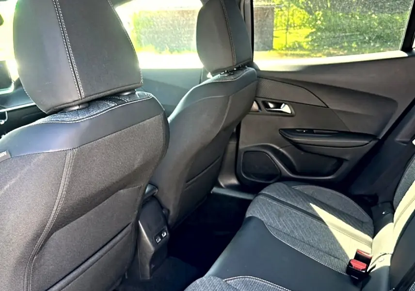 Vue intérieure arrière droite du Peugeot 2008 1.2 100 allure 2025 avec sièges tissu noir et gris et portes noires.