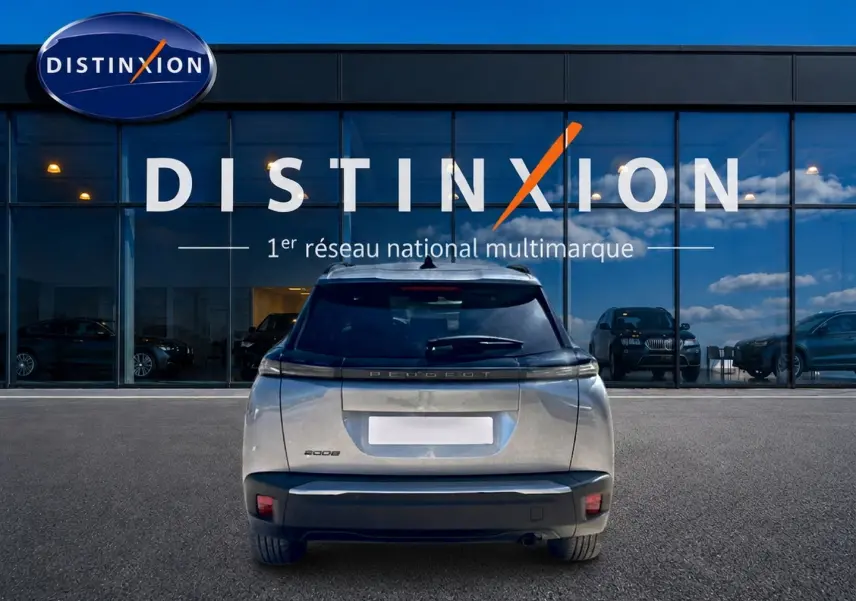 Vue arrière d’un Peugeot 2008 gris artense 2025 garé devant une vitrine avec logo Distinxion.