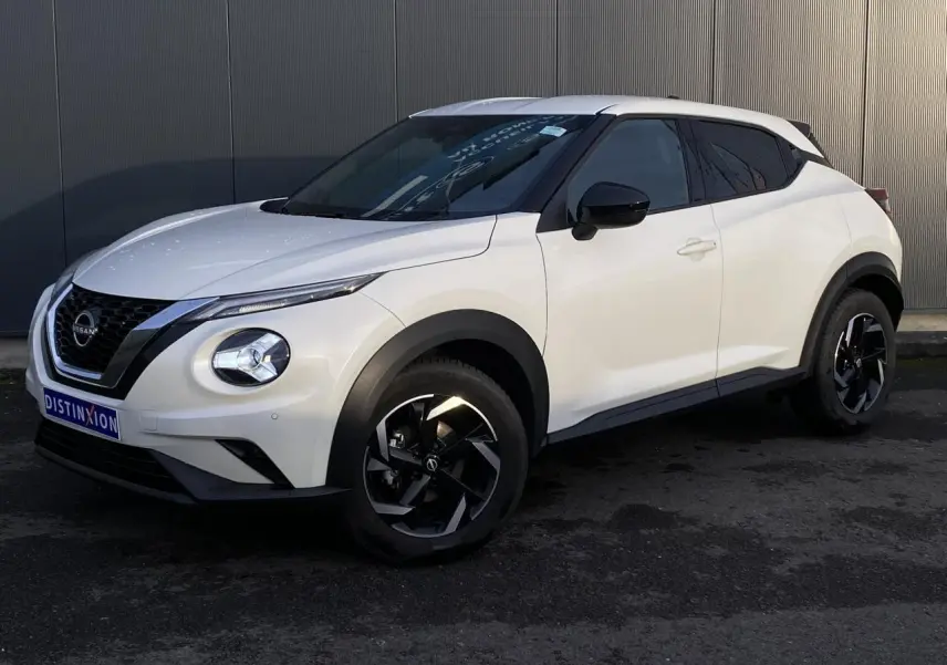 Nissan Juke blanc perle en vue 3/4 avant droit, avec jantes alliage noires et toit blanc contrasté.