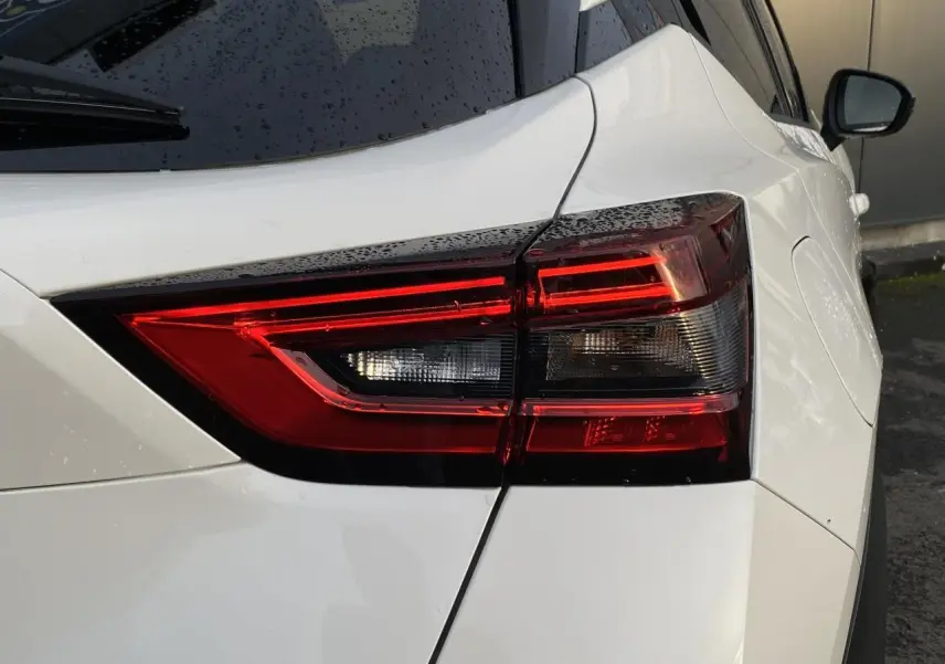 Gros plan sur le feu arrière droit d'un Nissan Juke blanc perle 2024, soulignant ses lignes modernes et épurées.