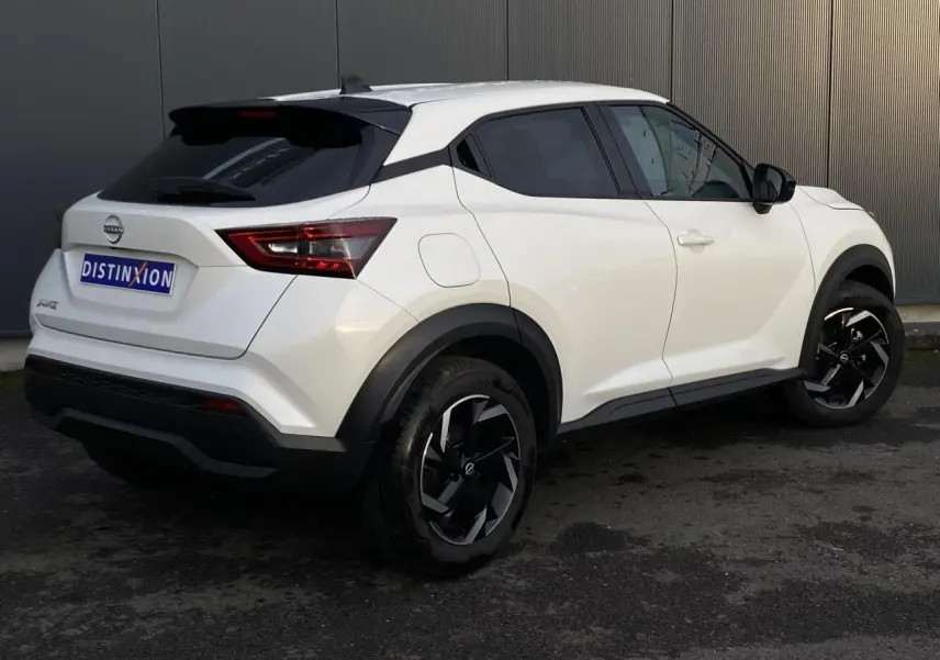 Nissan Juke blanc perle en 3/4 arrière droit, avec jantes alliage noires et toit noir contrasté.