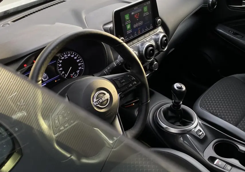 Vue intérieure côté conducteur du Nissan Juke DIG-T 114 N-Connecta 2024, volant cuir, écran tactile et levier de vitesse manuel.