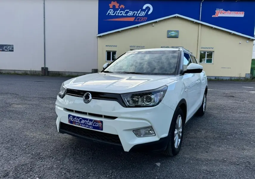 SUV SsangYong Tivoli blanc en 3/4 avant droit, avec calandre noire et phares anguleux visibles sur parking.