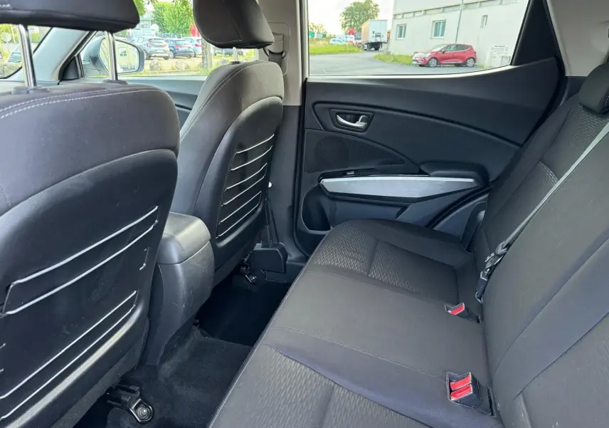 Vue intérieure côté droit des sièges arrière noirs du SsangYong Tivoli blanc 2016, avec appuie-têtes et ceintures visibles.