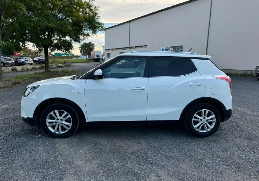 Vue de profil côté gauche d'un SsangYong Tivoli blanc 2016, SUV compact à cinq portes sur un parking extérieur.