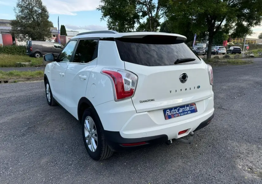 Vue 3/4 arrière droite d'un SsangYong Tivoli blanc 2016 avec hayon teinté et attelage visible sur parking.