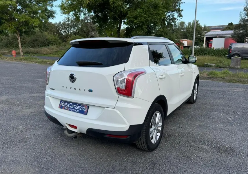 Vue 3/4 arrière droite d'un SsangYong Tivoli blanc 2016 avec attelage et vitres arrière teintées.