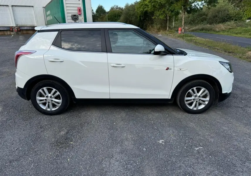 Vue latérale côté gauche d'un SsangYong Tivoli blanc 2016 avec vitres teintées et jantes alliage.