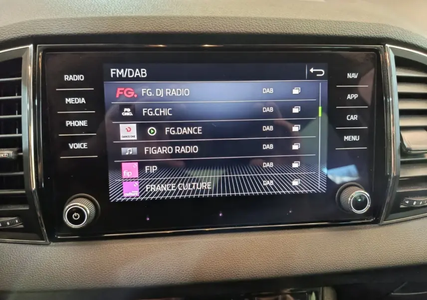 Écran tactile central de la Skoda Karoq blanc 2024 affichant les stations radio FM/DAB, vue de face intérieure.