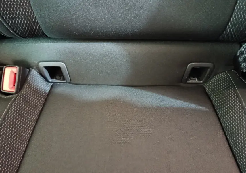 Gros plan sur la banquette arrière noire du Skoda Karoq 2024, montrant les fixations Isofix et la ceinture de sécurité rouge.