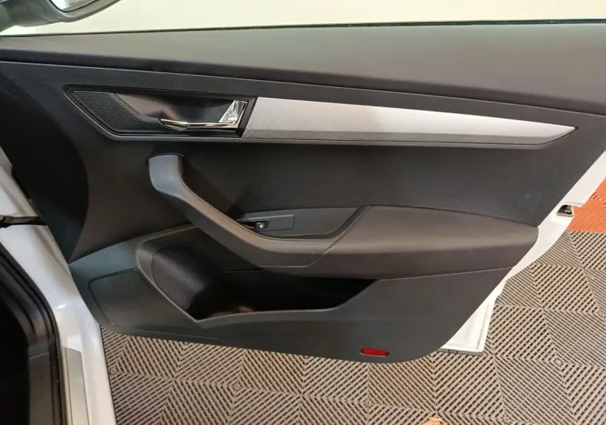 Vue intérieure de la porte avant gauche blanche du Skoda Karoq 2024 avec garniture noire et insert argenté.
