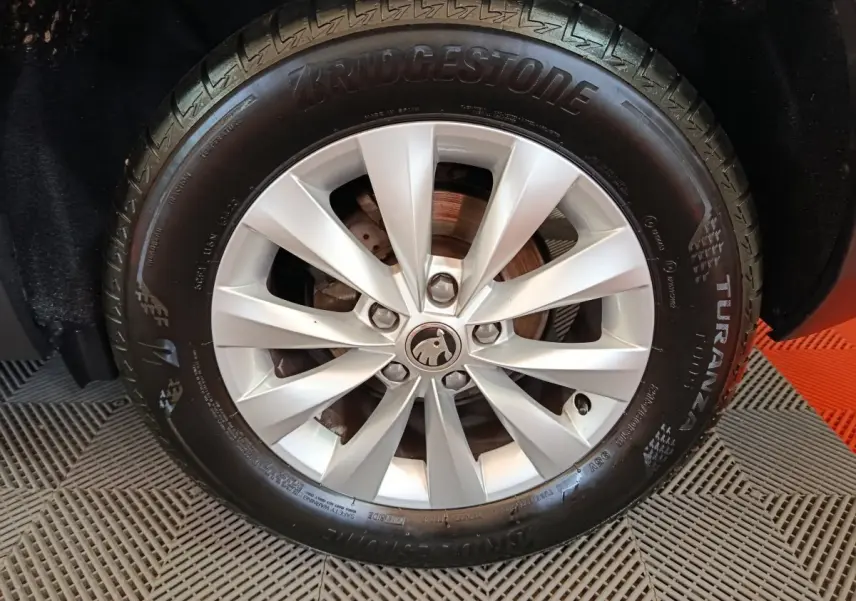 Gros plan sur la roue avant droite avec jante argentée et pneu Bridgestone Turanza du Skoda Karoq blanc 2024.