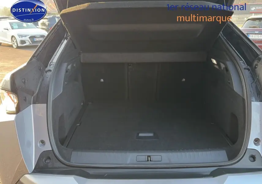 Coffre ouvert vu de l'arrière d'un Peugeot 3008 gris 2025, montrant un espace de chargement spacieux et propre.