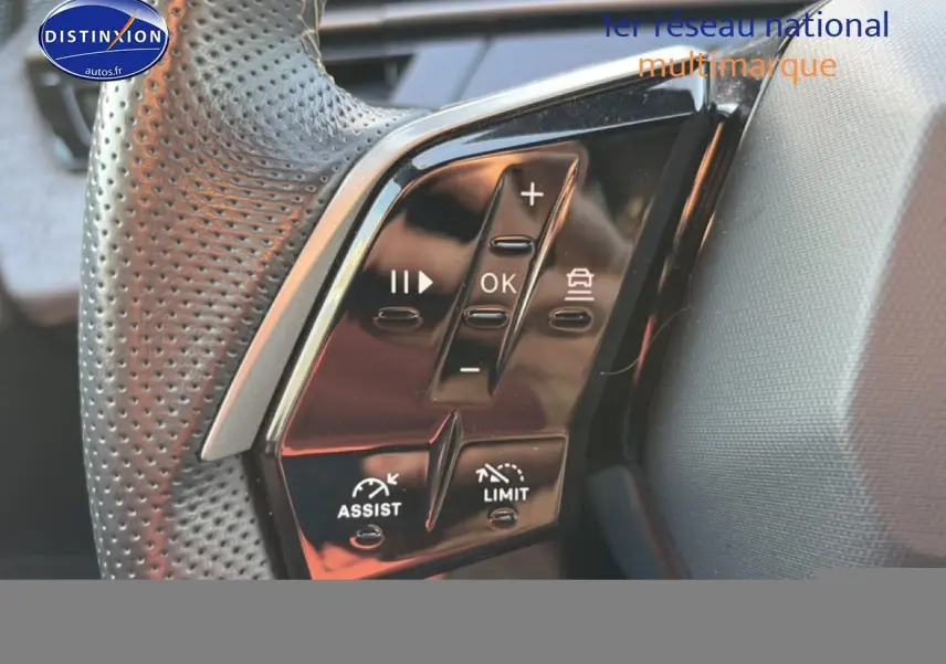 Gros plan sur les commandes noires du volant en cuir perforé du Peugeot 3008 gris 2025, côté gauche.